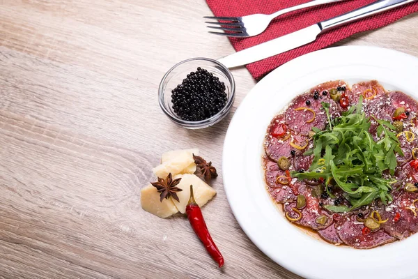 Biftek carpaccio roka ve ahşap masada siyah havyar. Üst Manzara. düz yat