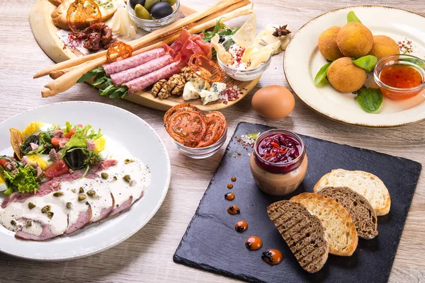 Salatalı bulaşıklar, arancini, ahşap bir masada kulübe tahtası. düz yatış, üst görünüm