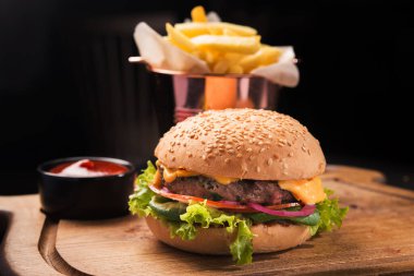 Tahta tahtada, ketçaplı ve patates kızartmalı klasik bir burger. Fast food turu.