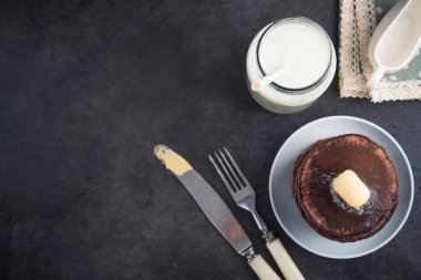 Tereyağı ve şişe sütle kaplı bir yığın çikolatalı krep. en üstteki görünüm