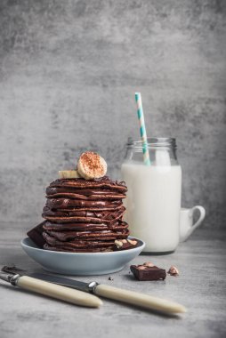 Taş bir masanın üzerinde çikolata, muz ve süt şişesi olan lezzetli bir krep. Yüksek kalorili kahvaltı..