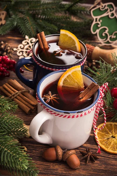 Christmas mulled red wine in cup with spices on a wooden table. Holiday food background.