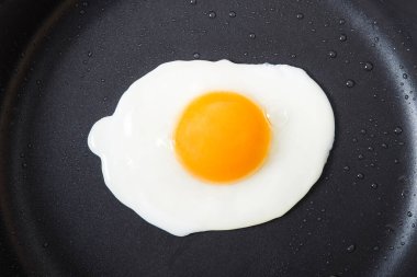 Kavanozdaki siyah metal tavada bir sahanda yumurta. Mutfakta yemek pişirmek. Üst görünüm.