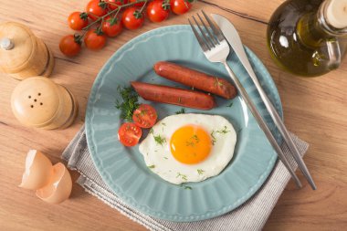 Mutfak masasında kızarmış yumurta, domuz sosisi ve taze domateslerden oluşan lezzetli bir kahvaltı..