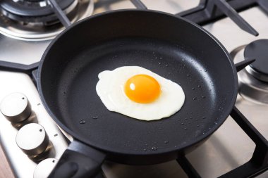 Kavanozdaki siyah metal tavada bir sahanda yumurta. Mutfakta yemek yapmak..