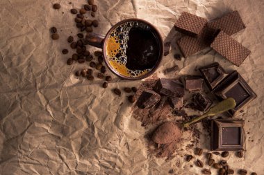 Büyük parça koyu çikolata, kakao tozu ve kağıt üzerinde kahve fincanı. Üst Manzara. Boşluğu kopyala