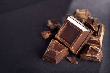 Siyah kağıda yazılmış lezzetli siyah çikolata parçaları. Tatlı ve kalorili yemek..