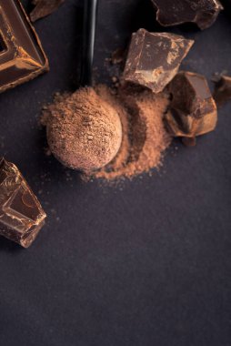 Büyük siyah çikolata parçaları ve siyah kaşıkta kakao tozu. Üst Manzara. Boşluğu kopyala