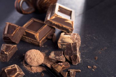 Siyah kağıda yazılmış lezzetli siyah çikolata parçaları. Tatlı ve kalorili yemek..