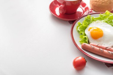 Yağda yumurta ve ızgara sosis, beyaz bir masada taze marul yaprağı. Sabah sağlıklı kahvaltı.