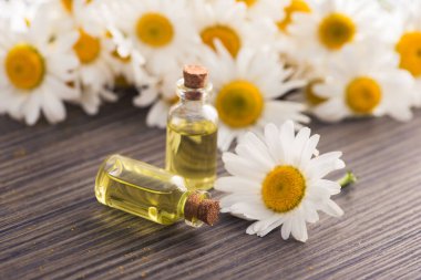 Cam şişe, ahşap bir masada çiçekli papatya yağı aromalı. Kozmetik ve tıbbi organik sıvı kavramı.