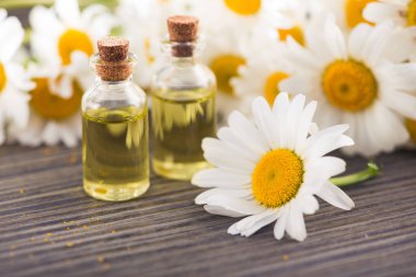 Cam şişe, ahşap bir masada çiçekli papatya yağı aromalı. Kozmetik ve tıbbi organik sıvı kavramı.