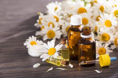 Cam şişe, ahşap bir masada çiçekli papatya yağı aromalı. Kozmetik ve tıbbi organik konsept.