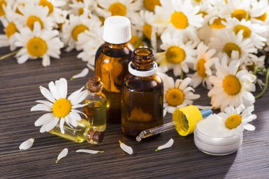 Cam şişe, ahşap bir masada çiçekli papatya yağı aromalı. Kozmetik ve tıbbi organik konsept.