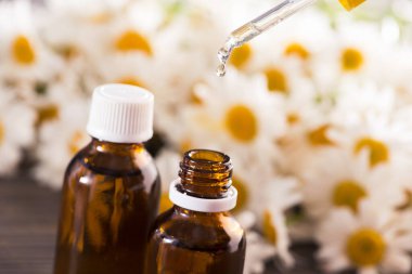 Cam şişe, ahşap bir masada çiçekli papatya yağı aromalı. Kozmetik ve tıbbi organik konsept.