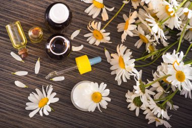 Cam şişe, ahşap bir masada çiçekli papatya yağı aromalı. Kozmetik ve tıbbi organik konsept. Üst Manzara. düz yat