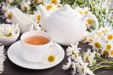 Masasında çiçekler olan bir fincan papatya çayı. Sağlıklı doğal içecek..