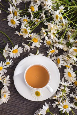 Masasında çiçekler olan bir fincan papatya çayı. Sağlıklı doğal içecek. en üstteki görünüm