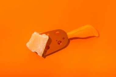 Turuncu arka planda parlak peynir ve bıçak kavramı. Yaratıcı besin düzlüğü. Üst görünüm