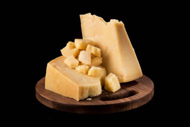 Parmesan peynirinin lezzetli ve taze parçalarını bölme tahtasında, siyah arka planda..