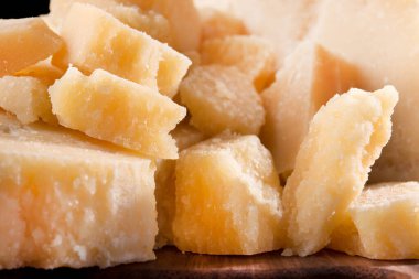 Parmesan peynirinin lezzetli ve taze parçalarını bölme tahtasında, siyah arka planda..