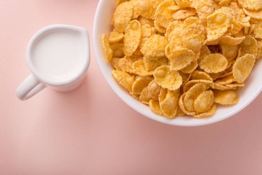 Ping pastel arka planında mısır gevreği olan bir kase. Lezzetli ve sağlıklı sabah kahvaltısı. Üst görünüm.