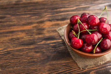 Tahta bir masada taze kırmızı kirazlar. Kırsal hasat konsepti. Biyolojik ve ekolojik meyveler. Metin için yer.
