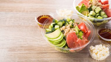 Taze salatalı plastik kap, ahşap bir arka planda salatalık, avokado, domates, greyfurt içerir. Lezzetli öğle yemeği..