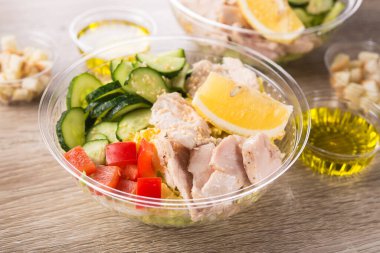 Ahşap zemin üzerinde taze salata olan plastik paket kutusu..