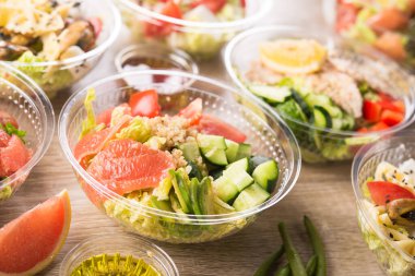 Taze salatalı plastik kap, ahşap bir arka planda salatalık, avokado, domates, greyfurt içerir. Lezzetli öğle yemeği..