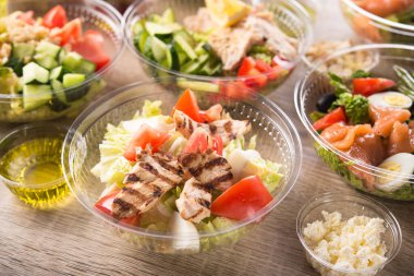 Ahşap zemin üzerinde taze salata olan plastik paket kutusu..