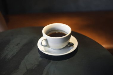 Siyah metal bir kafe masasında beyaz espresso fincanı.