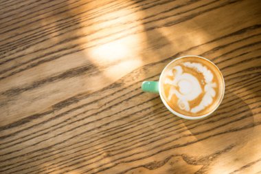 İtalyan kahvesi, sıcak ahşap bir masada kapuçino renginde turkuaz kahve fincanı. Metin için boşluk. Yukarıdan görünüm
