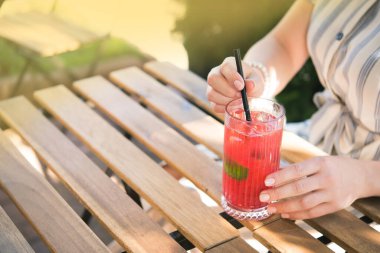 Genç ve güzel bir kız kafedeki ahşap masada soğuk içecek kokteyli içiyor. Yaz yaşam tarzı insanları.