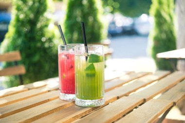 Soğuk yaz ferahlatıcı kokteyl ahududu ve limon, açık kafedeki ahşap masada kivi.