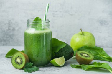 Yeşil detoks smoothie cam kavanozda ıspanak, kivi, limon, avokado hafif taşlı arka planda. Diyet ve vitamin meyveleri sağlıklı içecek, vejetaryen gıda konsepti.