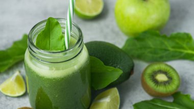 Yeşil detoks smoothie cam kavanozda ıspanak, kivi, limon, avokado hafif taşlı arka planda. Diyet ve vitamin meyveleri sağlıklı içecek, vejetaryen gıda konsepti.