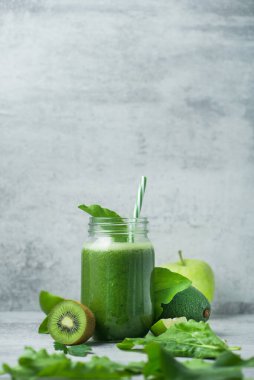 Yeşil detoks smoothie cam kavanozda ıspanak, kivi, limon, avokado hafif taşlı arka planda. Diyet ve vitamin meyveli sağlıklı içecek, vejetaryen gıda konsepti. Boşluğu kopyala