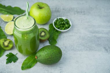 Yeşil detoks smoothie cam kavanozda ıspanak, kivi, limon, avokado hafif taşlı arka planda. Diyet ve vitamin meyveli sağlıklı içecek, vejetaryen gıda konsepti. Boşluğu kopyala