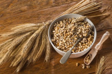 Tahta bir masada tohum ve buğdaylı kâse içinde lezzetli gevrek tanecikler. Kırsal sağlıklı mısır gevreği Sabah kahvaltısı.
