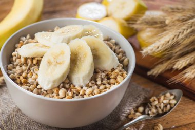 Tohum ve buğdaylı kasede gevrek gevrek, ahşap bir masada muz. Kırsal sağlıklı mısır gevreği Sabah kahvaltısı.