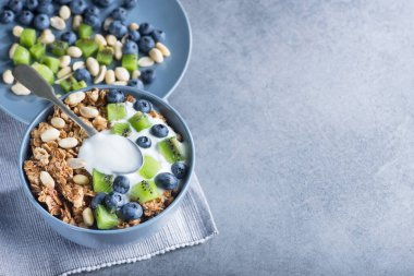 Mısır gevreğiyle sağlıklı kahvaltı yabanmersinli, kivili, yoğurtlu ve mavi kasede yer fıstıklı. Günaydın tatlı tatlı atıştırmalık. en üstteki görünüm