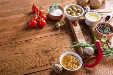 Taze salata malzemeleri (tuz, biber, zeytin, domates, biberiye, yağ) ahşap bir masa üzerinde kesme tahtasıyla birlikte. metin için boşluk kopyala