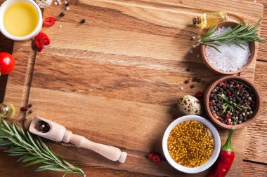 Taze salata malzemeleri (tuz, biber, zeytin, domates, biberiye, yağ) ahşap bir masa üzerinde kesme tahtasıyla birlikte. Üst Manzara. metin için boşluk kopyala