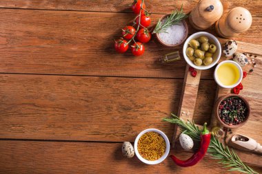 Taze salata malzemeleri (tuz, biber, zeytin, domates, biberiye, yağ) ahşap bir masa üzerinde kesme tahtasıyla birlikte. en üstteki görünüm