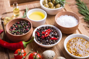 Taze salata malzemeleri (tuz, biber, zeytin, domates, biberiye, yağ) ahşap bir masa üzerinde kesim tahtasıyla birlikte.