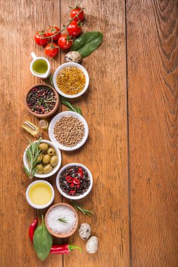 Tahta bir masada farklı baharatlar ve sebzeler. İtalyan yemek malzemeleri. Üst Manzara. metin için boşluk kopyala