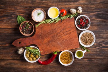 Taze salata malzemeleri (tuz, biber, zeytin, domates, biberiye, yağ) ahşap bir masa üzerinde kesme tahtasıyla birlikte. en üstteki görünüm