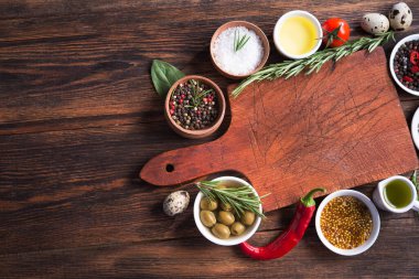 Taze salata malzemeleri (tuz, biber, zeytin, domates, biberiye, yağ) ahşap bir masa üzerinde kesme tahtasıyla birlikte. Üst Manzara. metin için boşluk kopyala