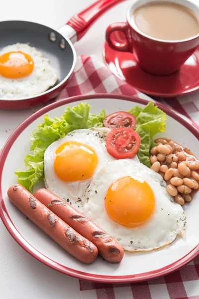 İngiliz kahvaltısı, kızarmış yumurta, fasulye, domates, sosis, taze marul yaprağı, kahve fincanı. Kırmızı yemek kavramı.